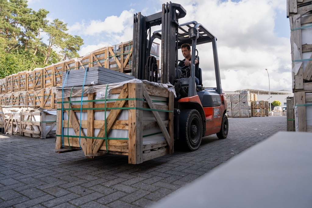 Een werknemer vervoert natuursteen met een heftruck.